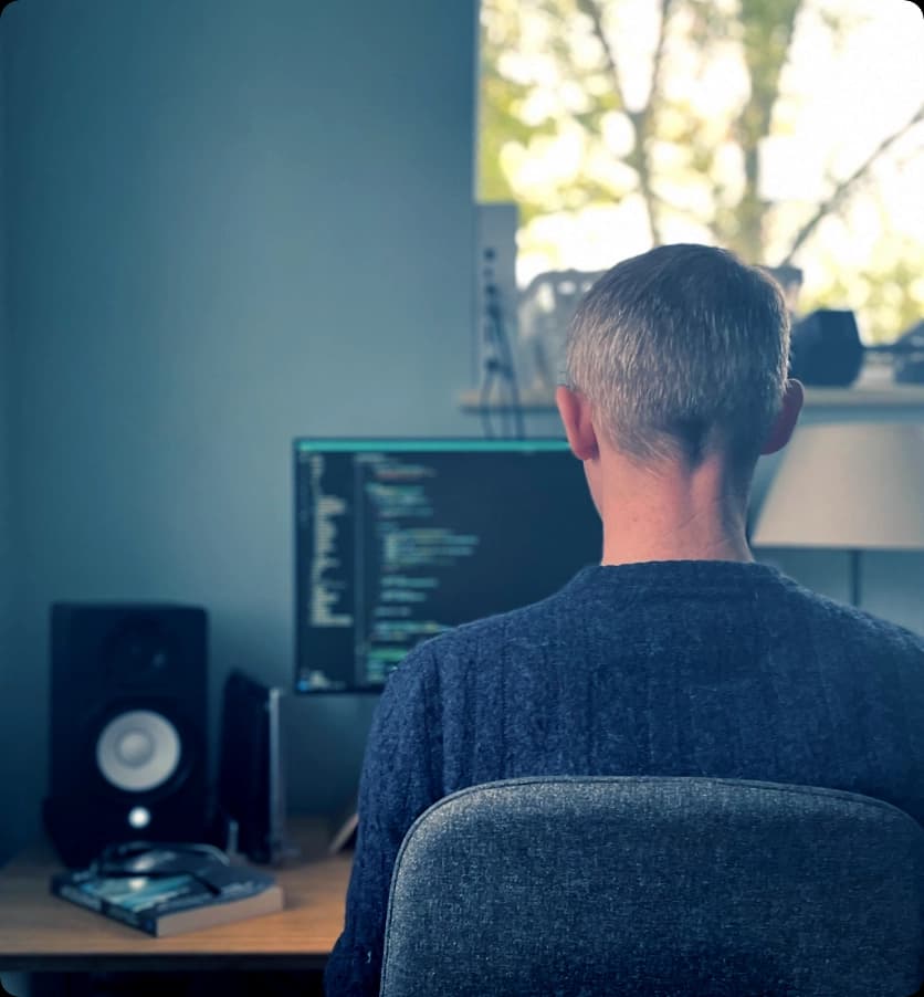 Andrew sitting at desk with code on screen